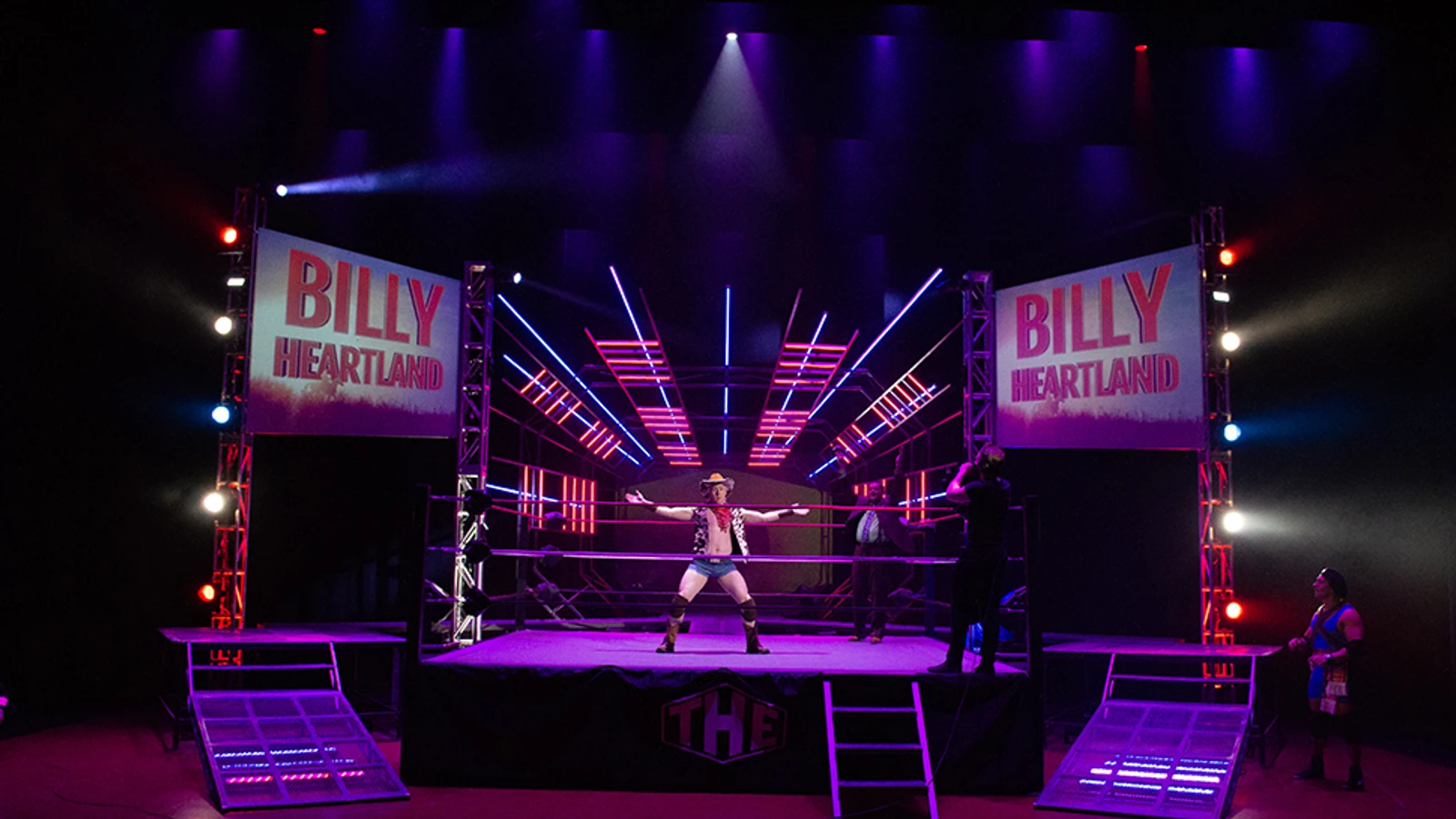Wrestler in Cowboy hat in front of lit up stage