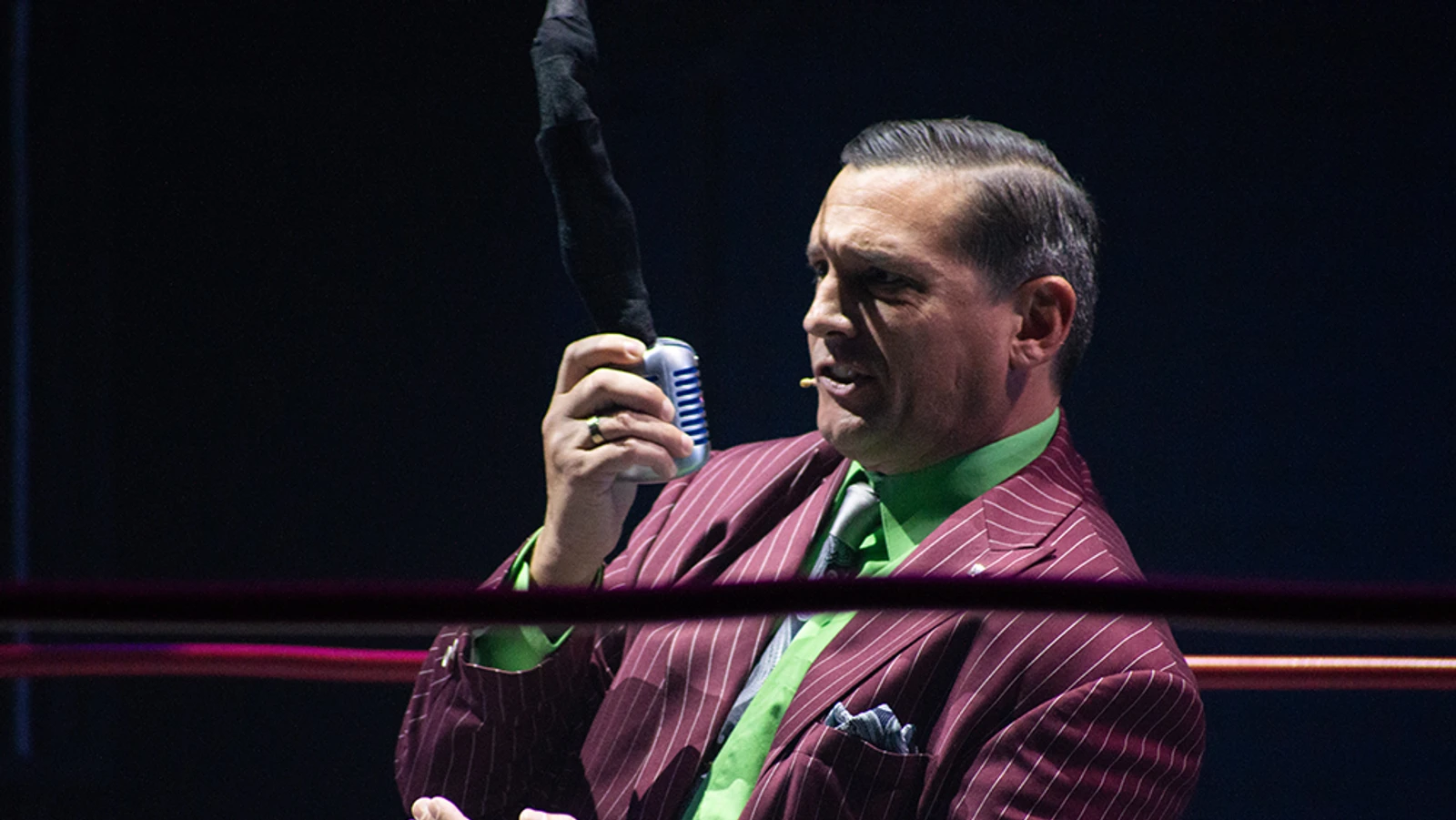 Man in purple suit holding a mic.